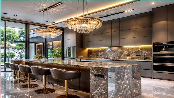 Modern luxury kitchen interior with a marble island, bar stools, and chandeliers.